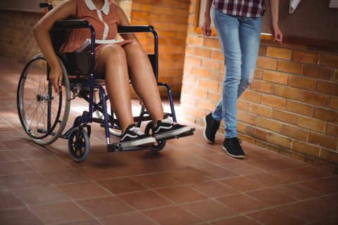 Schoolgirl with her disabled friend in corridor Schoolgirl with her disabled friend in corridor at school